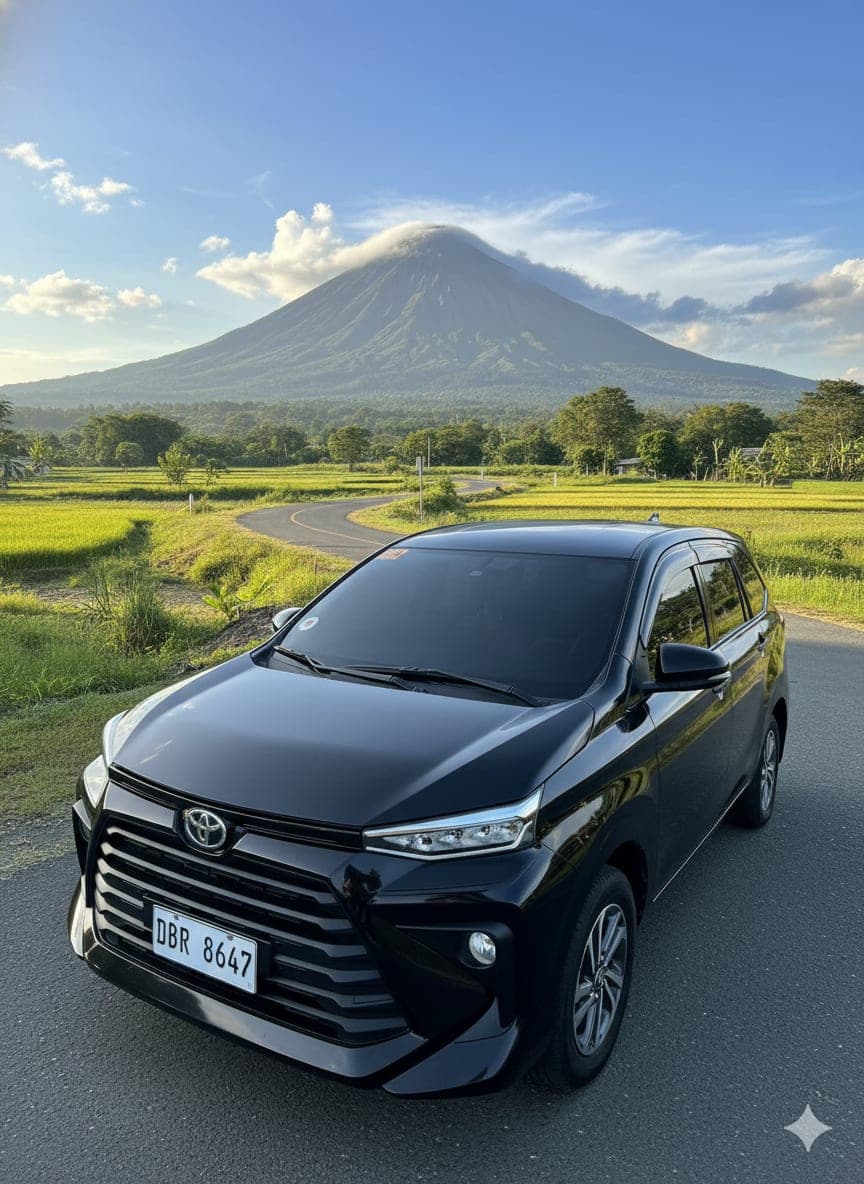 A black Toyota Avanza from our fleet on a country road with a mountain behind